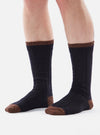 Close-up of a model's legs wearing navy wool hike socks with brown toe and cuff on a white background.