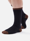 Close-up of a person wearing navy wool hike sock with brown toe and cuff on a white background.