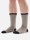 Close-up of a person wearing Stone Wool Hike Sock on a white background. The socks are gray with a ribbed texture and have a black toe and cuff.