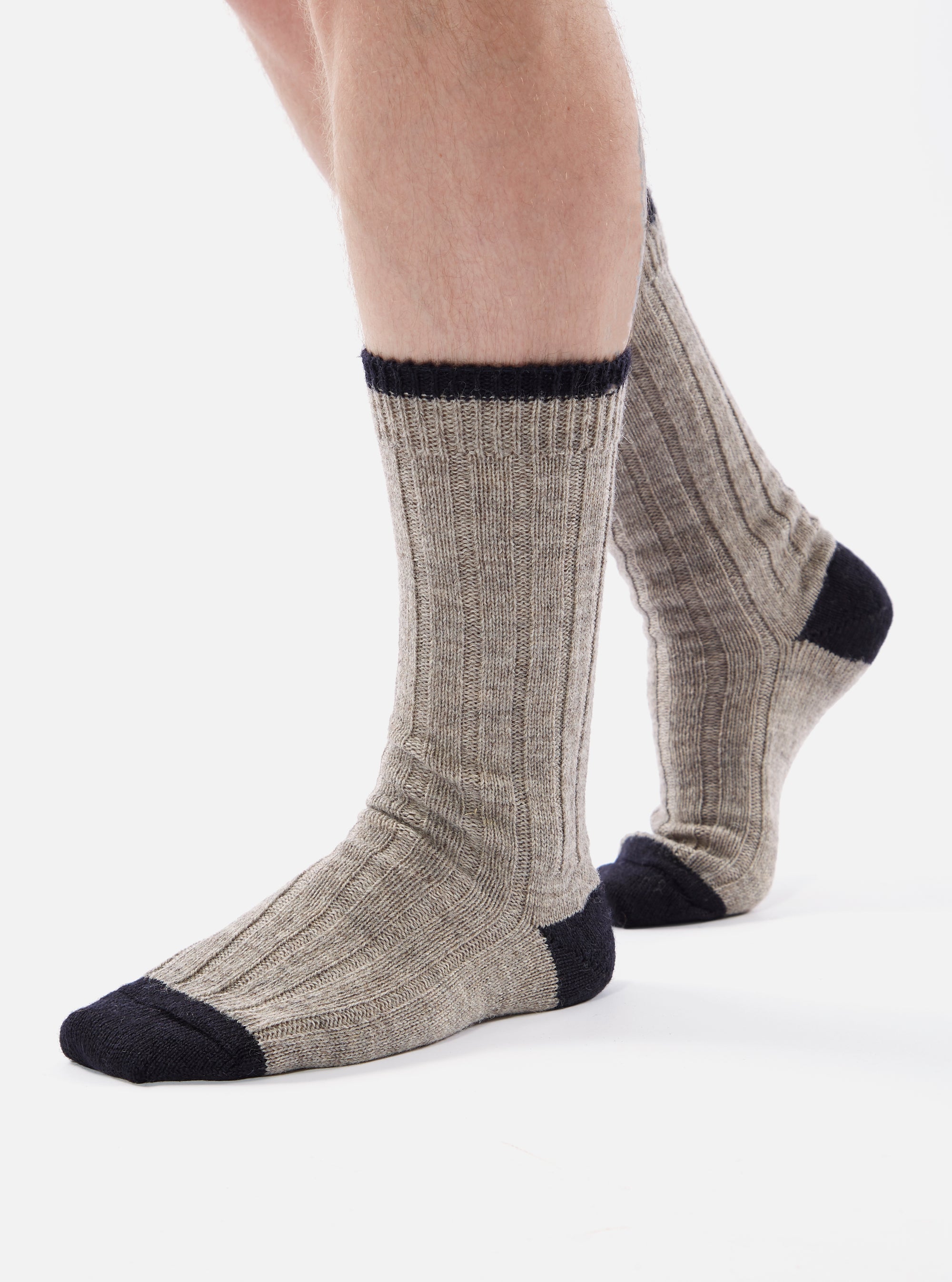 Close-up of a person wearing Stone Wool Hike Sock on a white background. The sock is a ribbed knit in a heathered gray color, with a black toe and cuff.