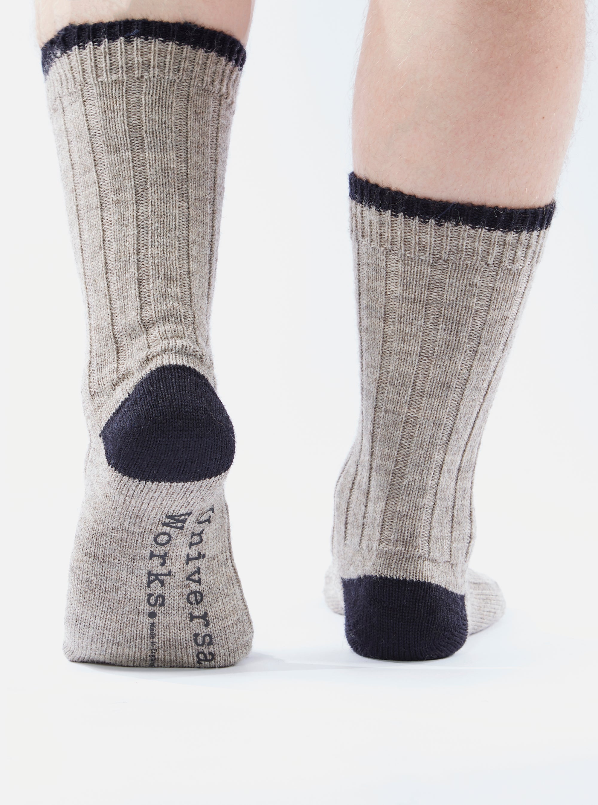 Close-up of the back of two legs wearing Stone Wool Hike Sock. The socks are gray with a black toe and top. The background is white.