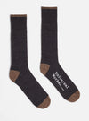 Two Charcoal Alpaca Wool Sock on a white background. The socks are charcoal with brown toes and cuffs. One sock has the words "Universal Works. Made in England" printed on it.
