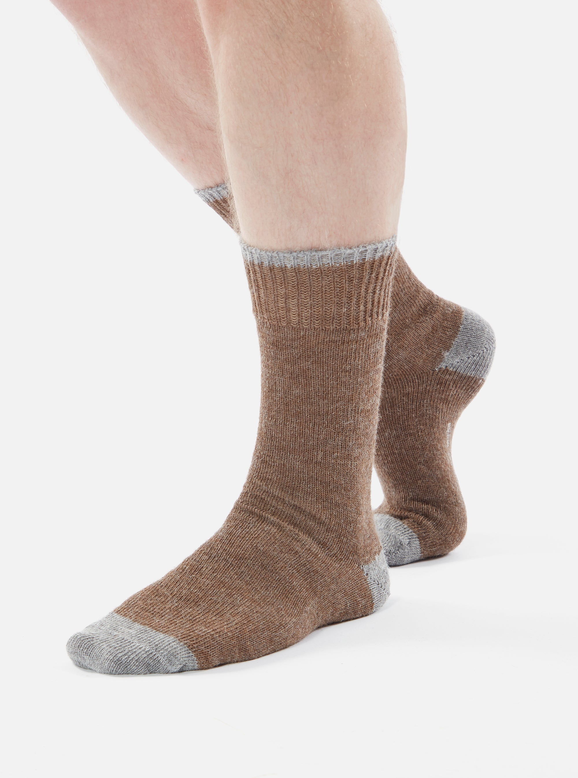 A person wearing Brown Alpaca Wool Socks with gray toe and top on a white background.