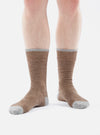 A person stands on a white background wearing Brown Alpaca Wool Socks. The socks are brown with gray toes and cuffs.