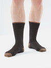 A pair of Charcoal Alpaca Wool Socks are shown on a person against a white background. The socks are charcoal with a brown toe, heel and cuff.
