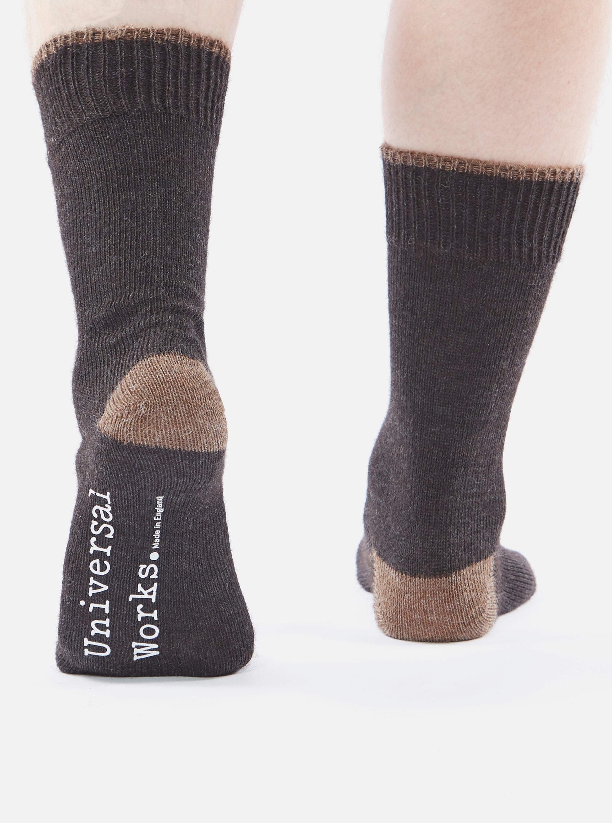 Close-up of a person wearing Charcoal Alpaca Wool Sock. The socks are charcoal with a brown toe and cuff. The background is white.