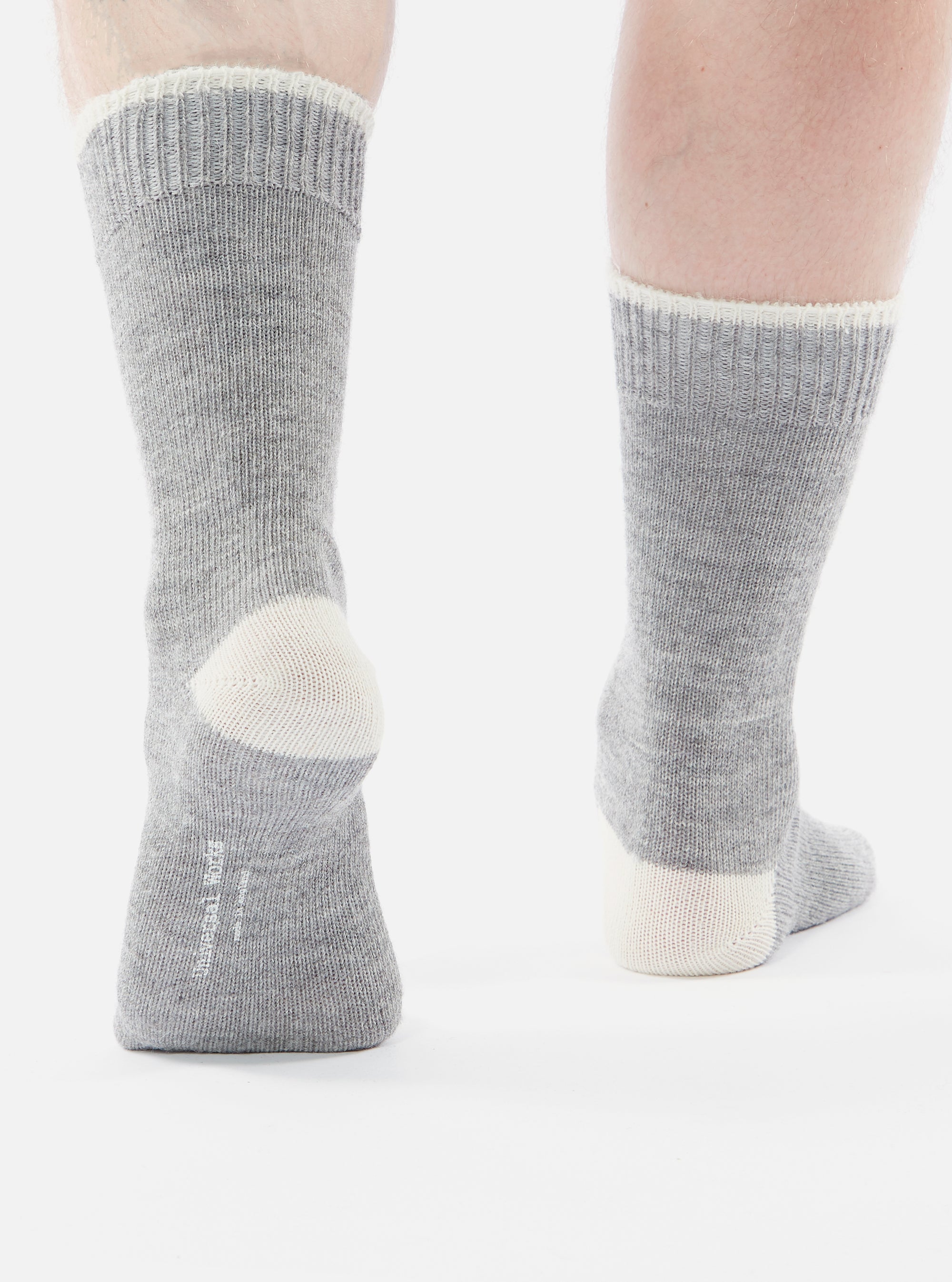 Close-up of a person wearing Grey Marl Alpaca Wool Sock on a white background. The sock is grey with a white heel and cuff.