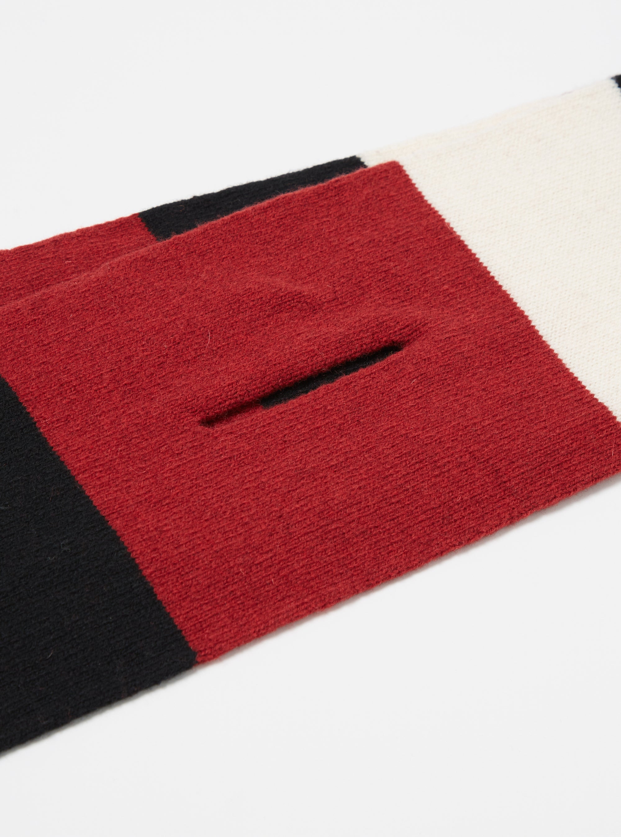Close-up of a Black/Red/Ecru Soft Wool Deluxe Football Scarf on a white surface. The scarf features stripes of black, red, and ecru wool.