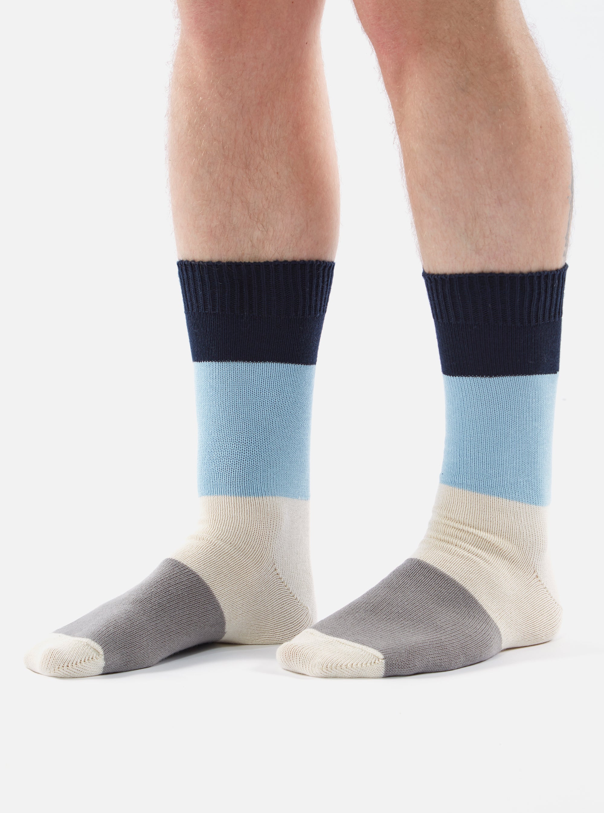 A pair of legs wearing the Navy/Sky Cotton Bold Stripe Sock, which features navy, sky blue, cream, and gray stripes. The socks are displayed against a white background.