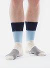 A person stands against a white background wearing Navy/Sky Cotton Bold Stripe Sock. The socks feature navy, sky blue, cream, and gray stripes.