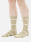 A model wears Dark Sand Tie Dye Knit Slub Socks. The knit socks are tan with white stripes. Shot in a studio with a white background.