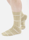 Close-up of a model wearing Dark Sand Tie Dye Knit Slub Sock on a white background. The socks are a light tan color with a knit texture and white stripes.