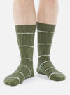 Close-up of a model wearing Olive Tie Dye Knit Slub Sock on a white background. The sock is olive green with white stripes.