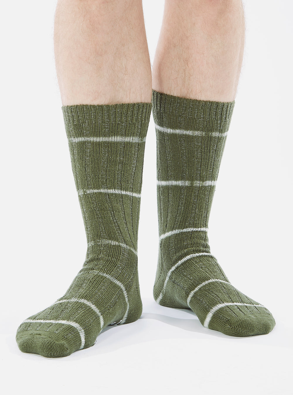 Close-up of a model wearing Olive Tie Dye Knit Slub Sock on a white background. The sock is olive green with white stripes.