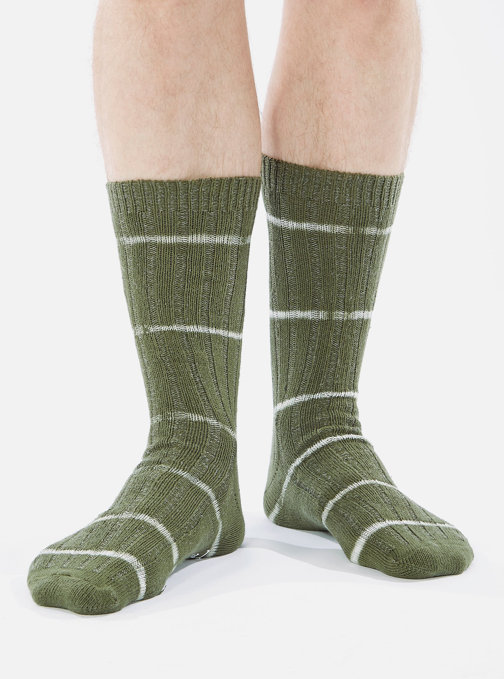 Close-up of a model wearing Olive Tie Dye Knit Slub Sock on a white background. The sock is olive green with white stripes.