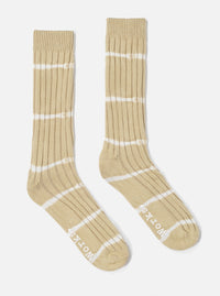 Studio shot of Dark Sand Tie Dye Knit Slub Sock. Ribbed knit with white tie dye stripes. 'Works' printed on foot. Soft cotton blend. On a white background.