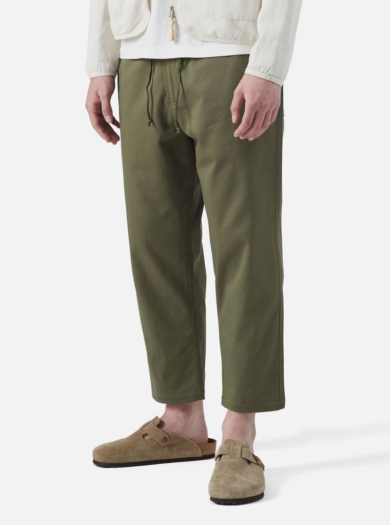 Model wearing Light Olive Twill Hi Water Trouser on a white background. The twill trousers are paired with suede Birkenstocks.