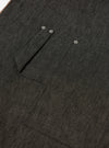 Close-up of the Black Selvedge Denim Apron showing the texture of the denim and pocket details. The apron is laid flat on a neutral surface.