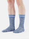A model stands against a white backdrop, showcasing the Navy Cotton Everyday Stripe Sock. The sock features a ribbed texture and blue and white stripes at the top.