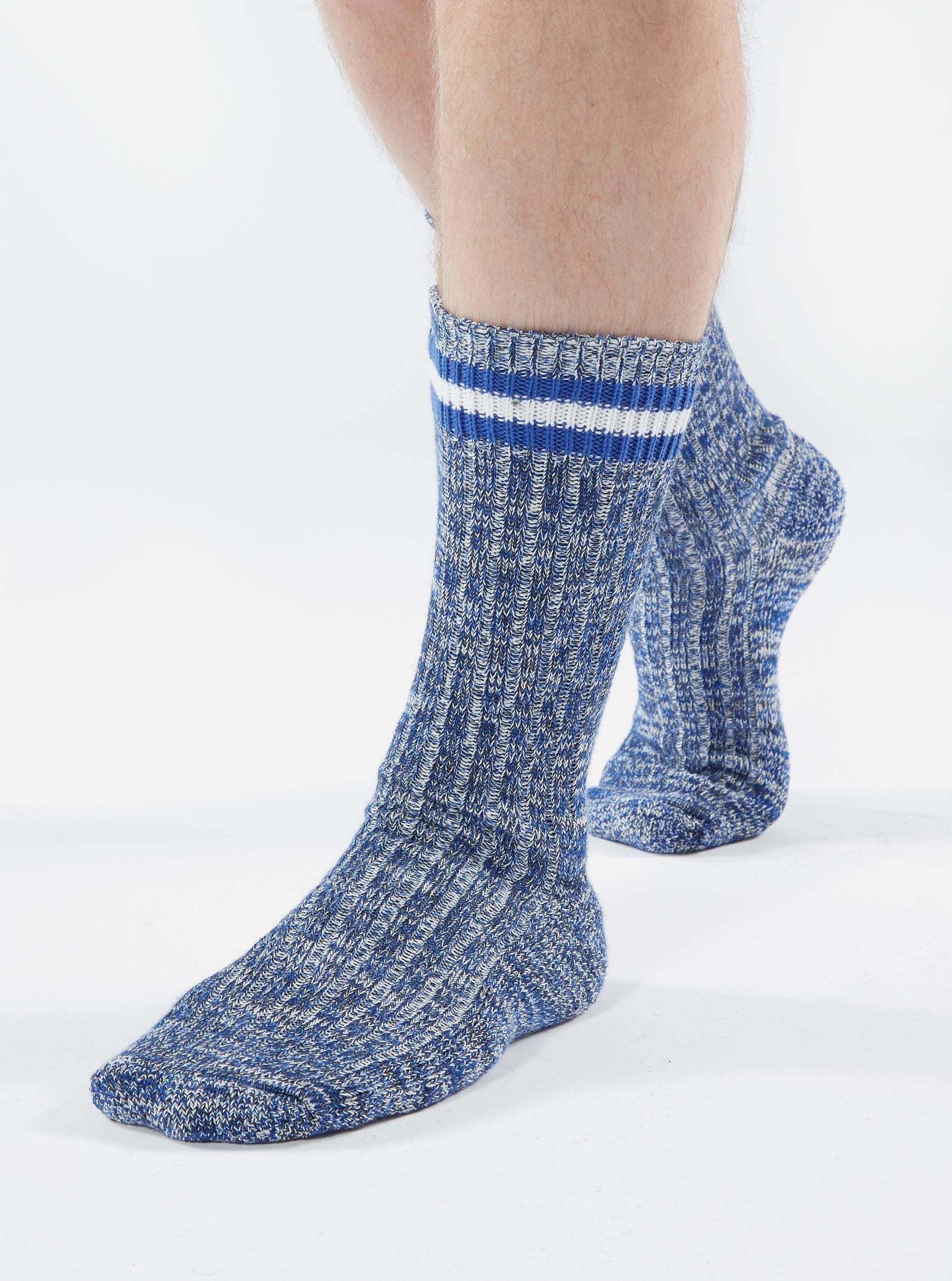 Close-up of a person wearing Navy Cotton Everyday Stripe Sock on a white background. The sock is blue with white stripes at the top.