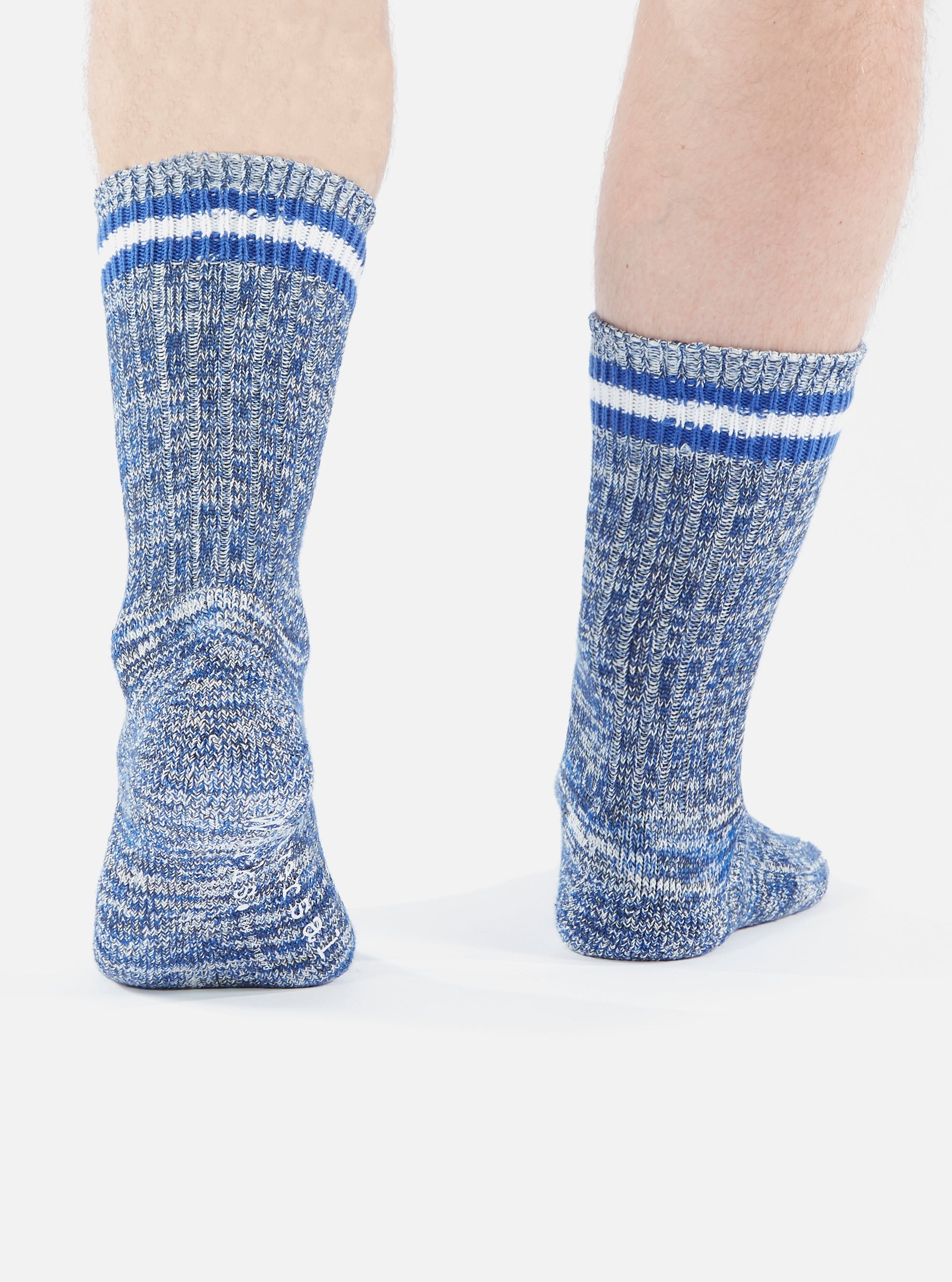 Close-up of a person wearing Navy Cotton Everyday Stripe Sock on a white background. The socks are blue and white with stripes at the top.