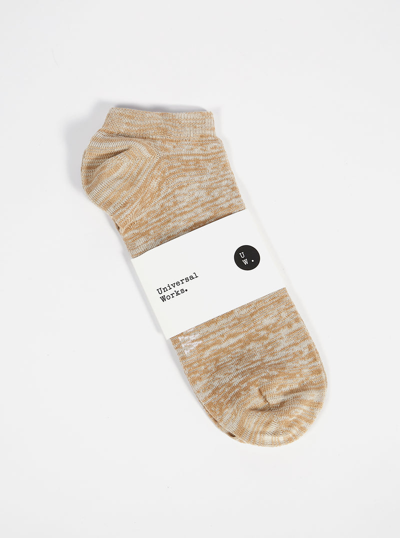 Studio shot of a Dark Sand Slub Knit Ankle Slub Sock on a white surface. The sock has a paper label around it.