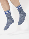 A person's legs wearing the Navy Cotton Everyday Stripe Sock, a blue and white striped sock, on a white background.