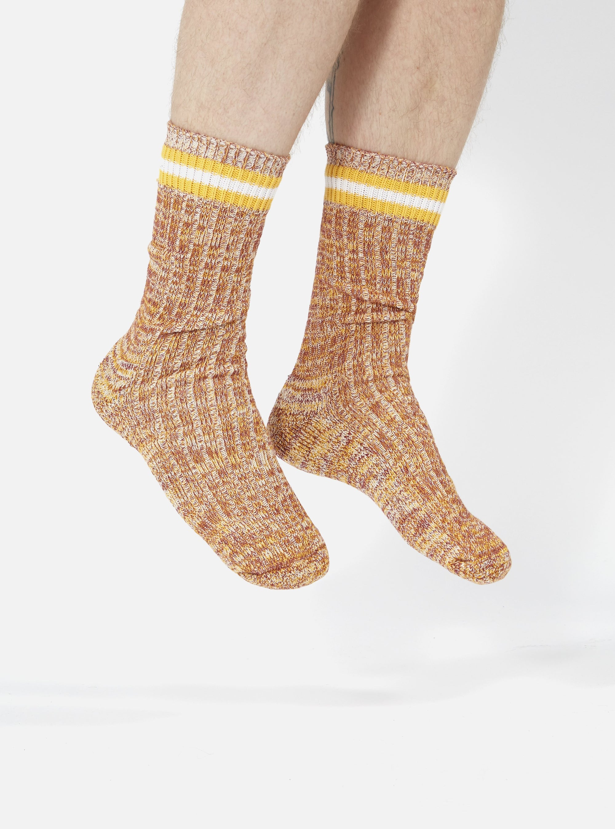 A person wearing Yellow Cotton Everyday Stripe Sock on a white background. The socks are ribbed and have yellow and white stripes at the top.