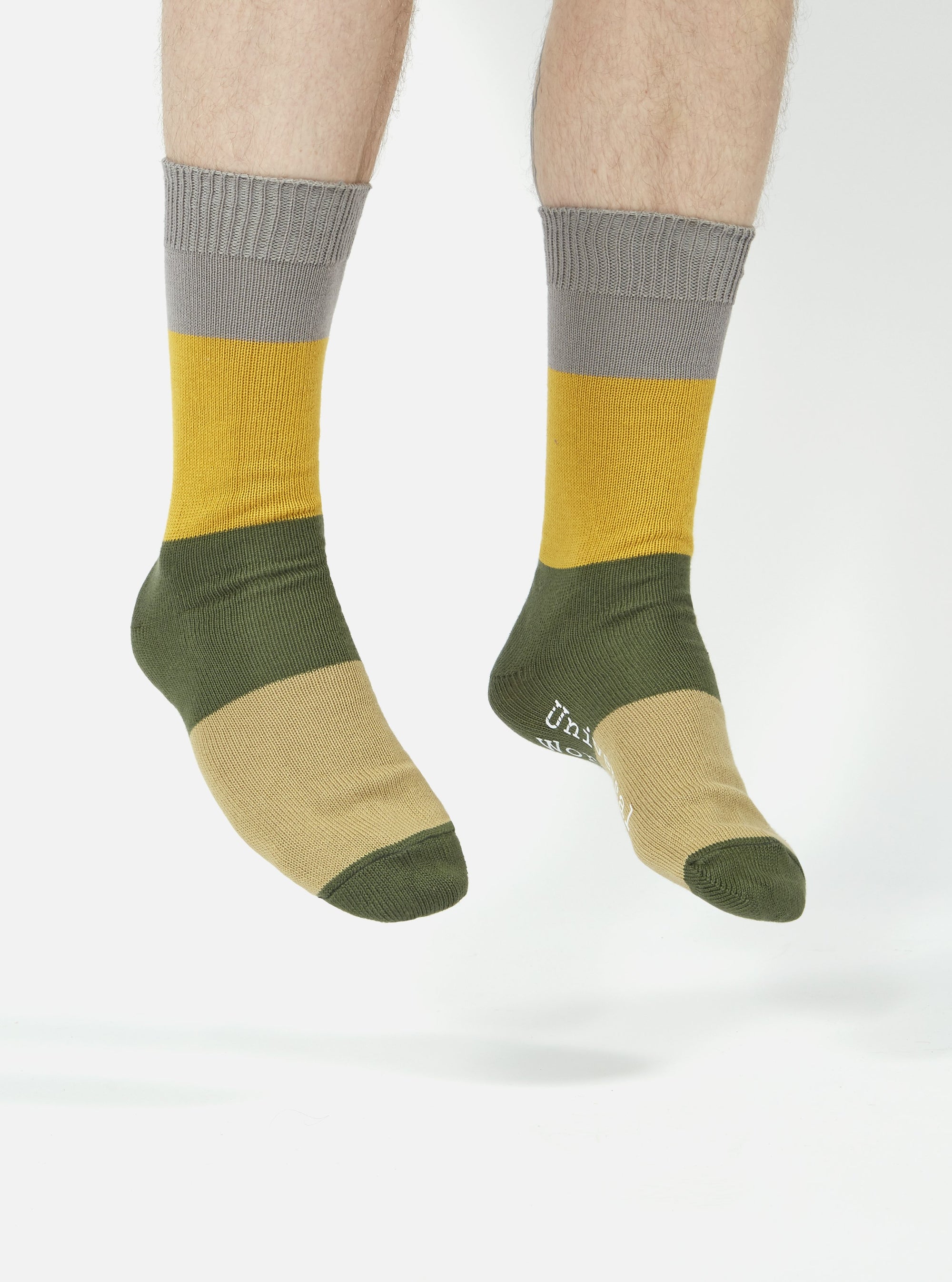 A pair of legs wearing Grey/Gold Cotton Bold Stripe Sock, with grey, gold, green and tan stripes. The background is white.