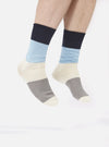 Close up of a person wearing Navy/Sky Cotton Bold Stripe Sock on a white background. The sock features navy, sky blue, cream, and gray stripes.