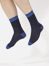 A model wearing Navy Merino Classic Sock, a navy sock with a blue toe and cuff, on a white background.