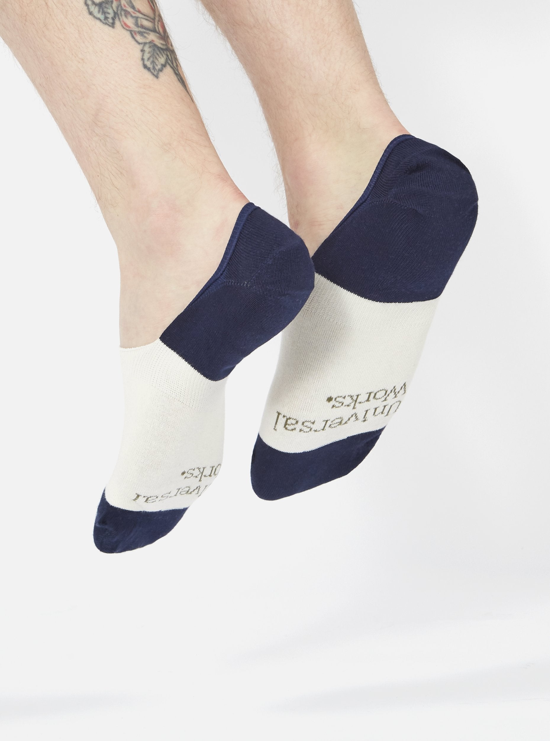 A person wearing Ecru/Navy Cotton Mix Knit No Show Sock. The socks are ecru with navy blue accents. The background is a plain white.