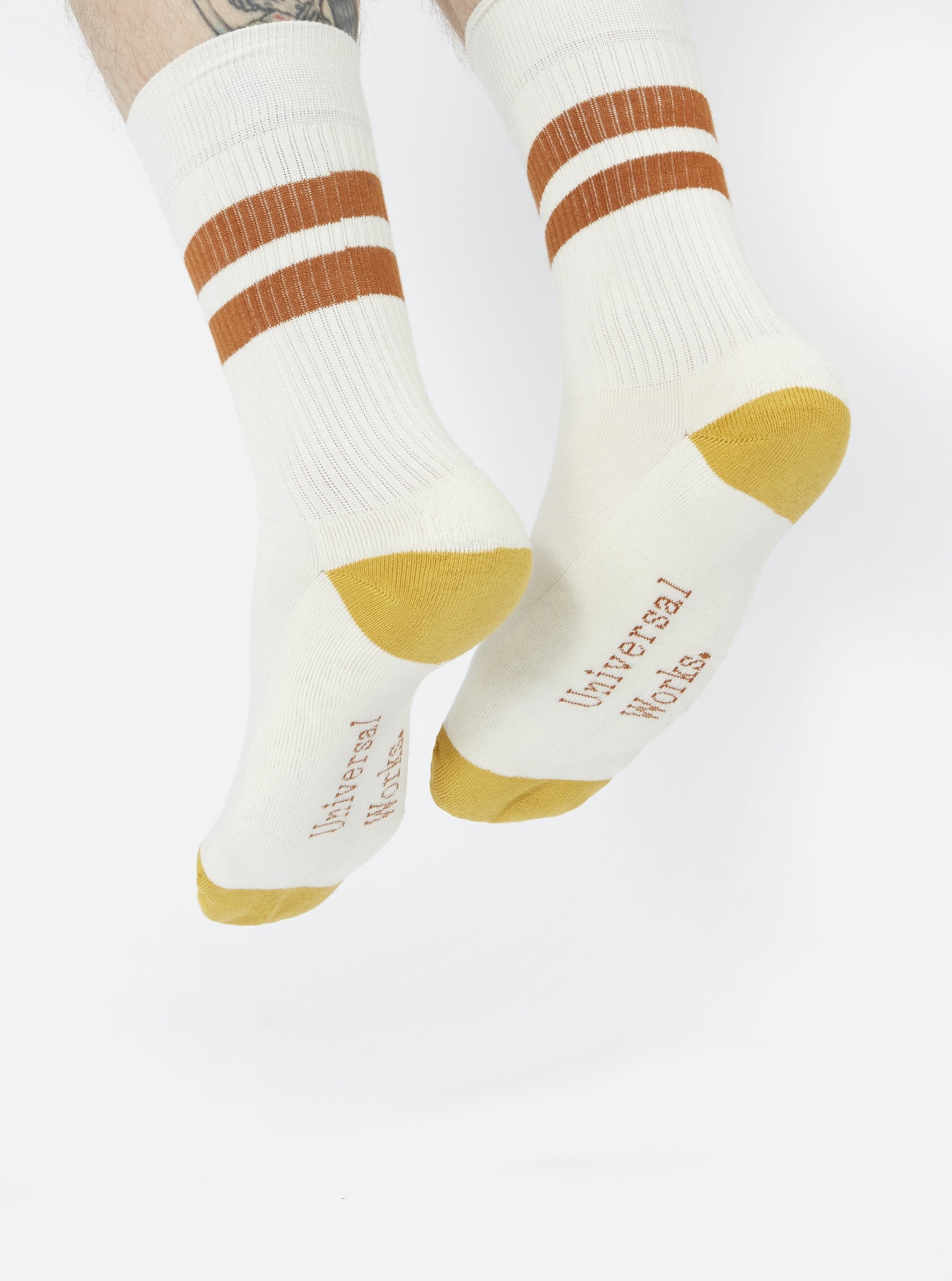 Close-up of Ecru/Orange Cotton Rib Sport Sock on a model against a white background. The sock features orange stripes and a ribbed texture.