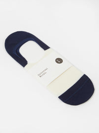 Close-up of the Ecru/Navy Cotton Mix Knit No Show Sock on a white surface. The sock features ecru and navy stripes and is held together by a Universal Works paper label.