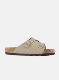 Studio shot of a Birkenstock Taupe Suede Zürich sandal on a white background. The sandal features a taupe suede upper and a cork footbed.